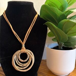 Golden metal rings pendant on suede cord necklace.